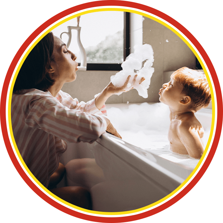 Mother and child blowing soap bubbles in a bathtub at sunset