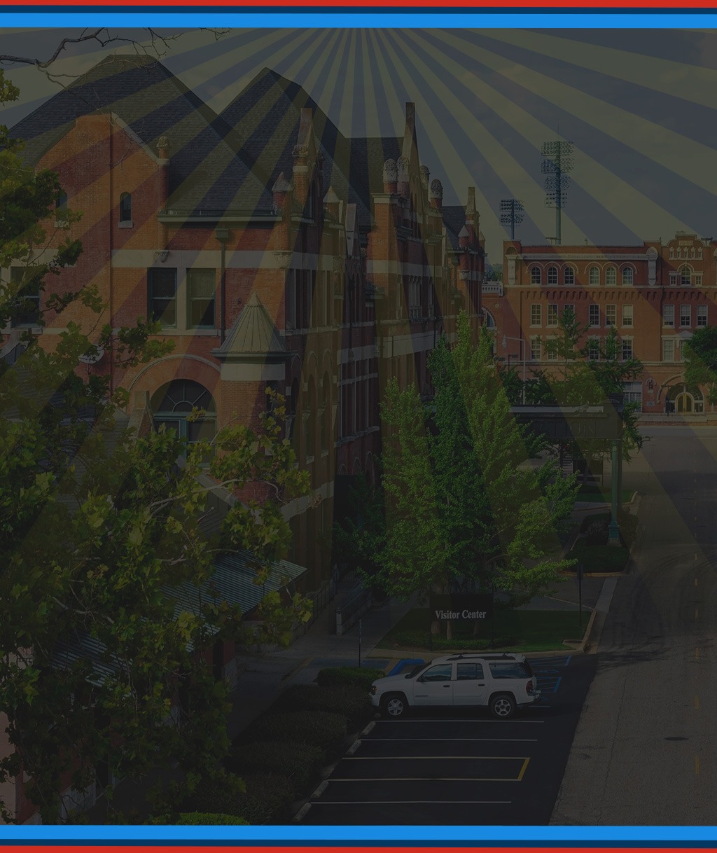 Sunburst rays over an aerial view of a campus building and parking lot